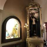 Ci spostiamo sul lato sinistro del tempio, ritrovandoci di fronte a una grande acquasantiera dalla forma insolitamente cilindrica, in cui si trova la statua in cartapesta di Sant'Antonio con in braccio Ges� bambino. L'edicola ha un tono sfarzoso, dettato dalle rifiniture dorate e illuminata da candeline laterali